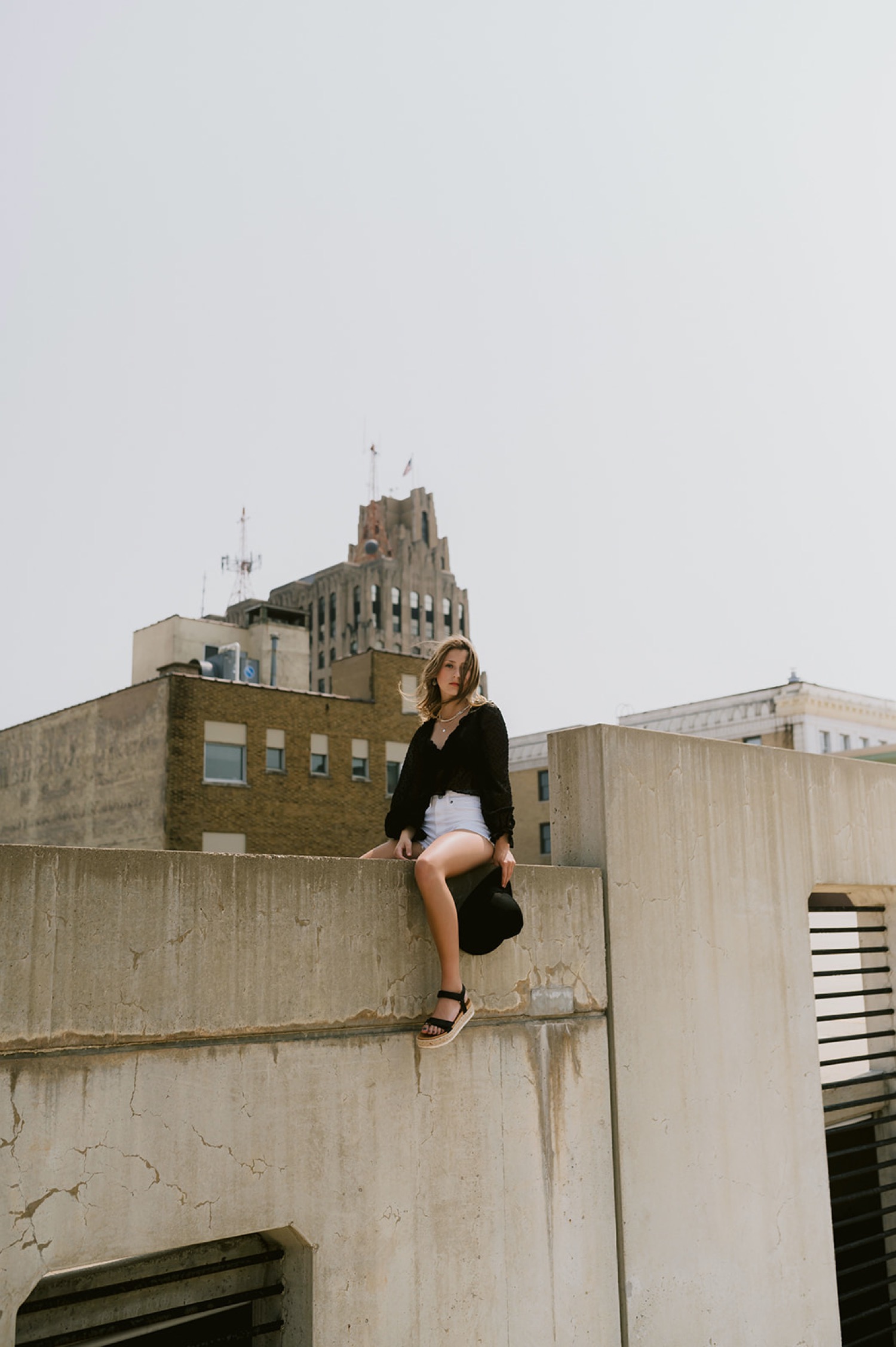 Girl sitting on the rooftop of a building during their senior photoshoot with Michigan senior and wedding photographer Mary Shelton