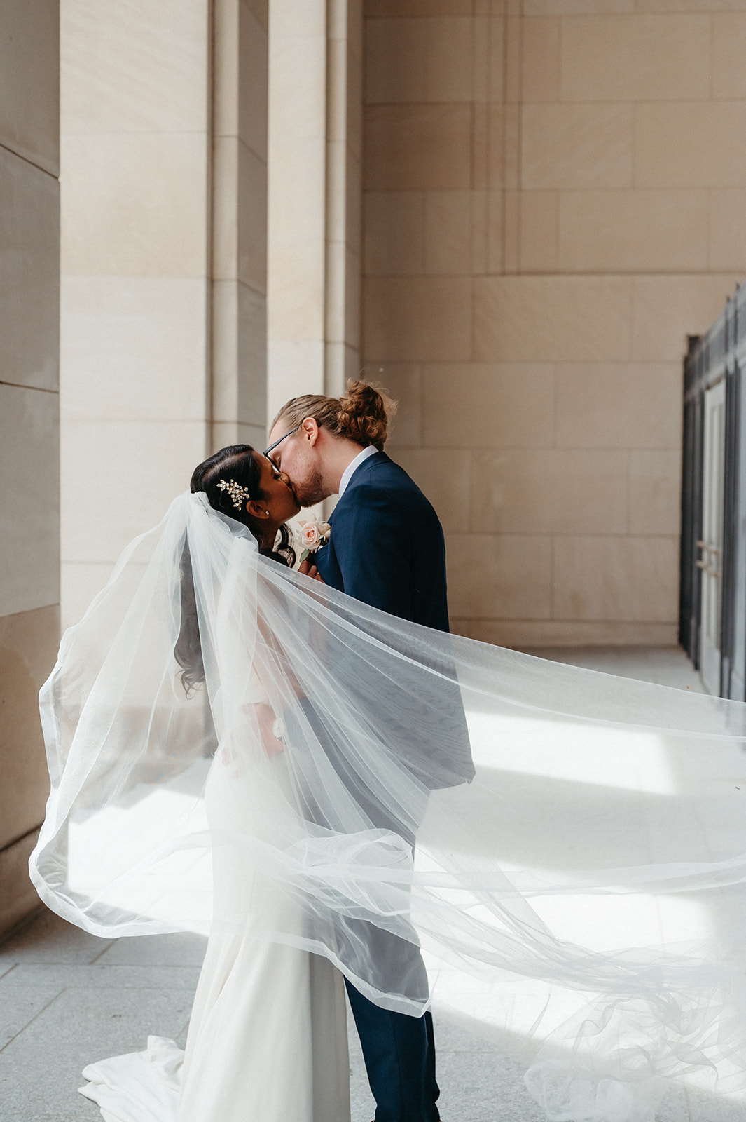 Couple sharing a kiss as bride's veil sways in the wind, taken by Michigan wedding photographer Mary Shelton